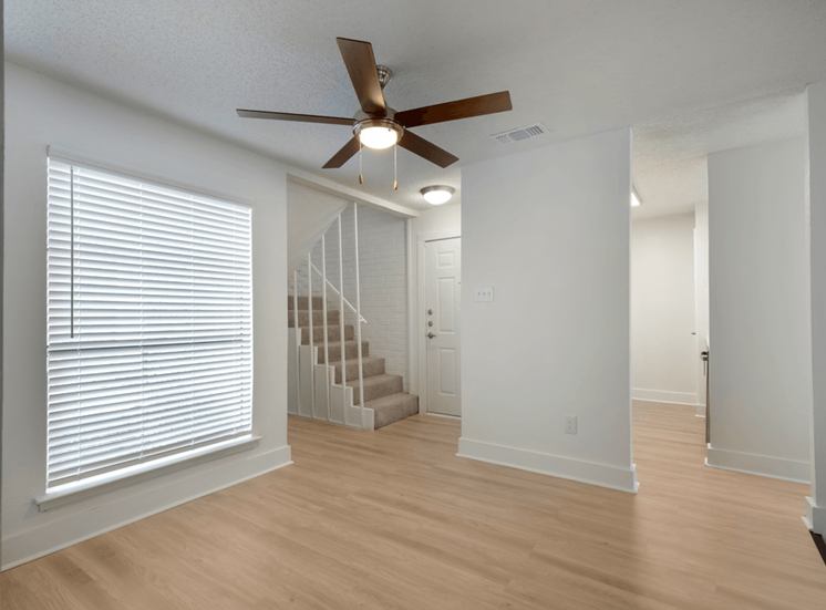 Entry way with carpeted stairs, ceiling fan, wood style flooring, large window with blinds